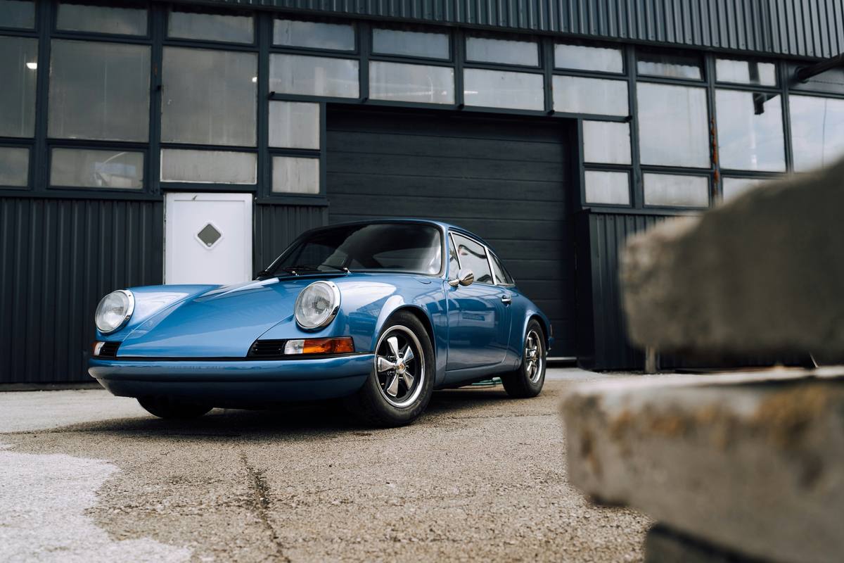 Porsche 911 clásico azul frente a un garaje